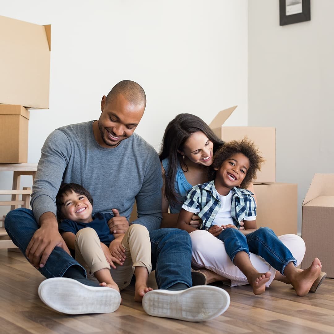 Happy family sitting on floor with moving boxes